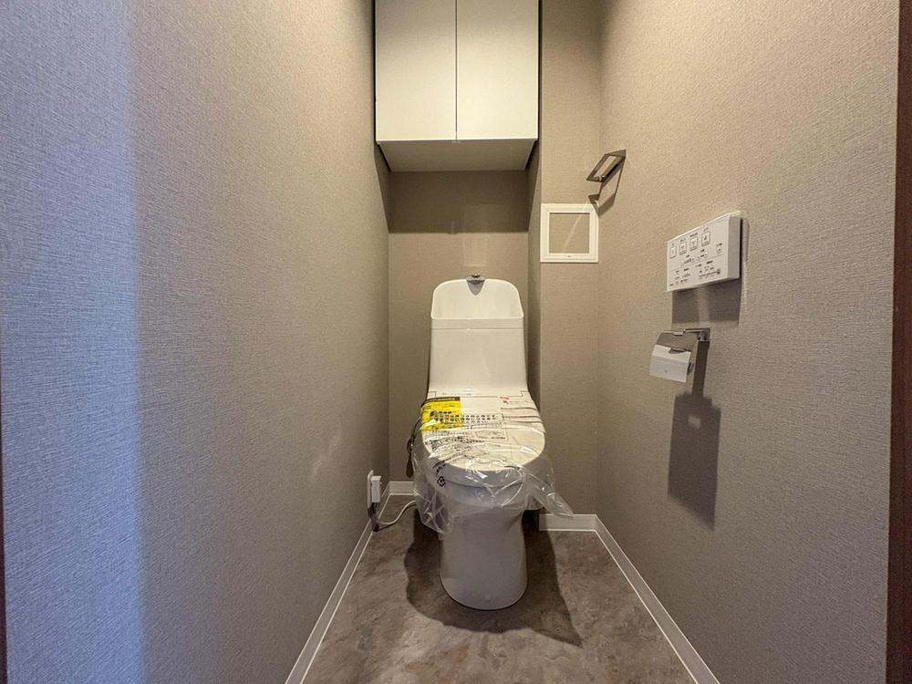 清潔感あふれる新しいトイレは、上部に収納も完備しており、空間をすっきりと保てます。家族みんなが快適に使える、機能的なサニタリー空間です。
