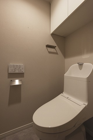 清潔感のある、温水洗浄便座付きのトイレです。トイレ周りで使う物の収納に便利な、上部吊戸棚付き。