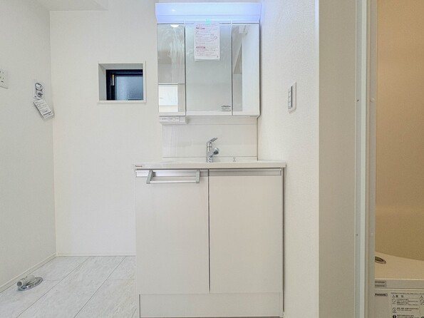 ３号棟【三面鏡洗面化粧台】  ミラーを手前に引けば、楽な姿勢で髭剃りやメイクができます。合わせ鏡にすればヘアスタイルのチェックもラクラク。洗面化粧台のミラー裏にはたっぷり入る収納スペースを設けています