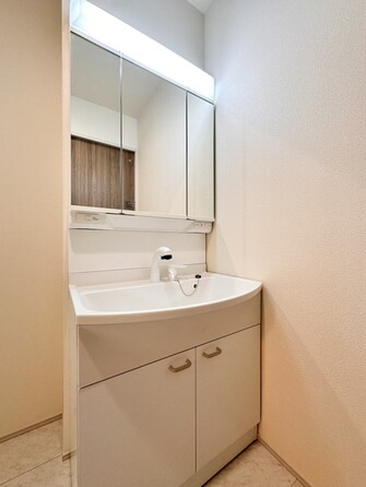 【三面鏡洗面化粧台】  ミラーを手前に引けば、楽な姿勢で髭剃りやメイクができます。合わせ鏡にすればヘアスタイルのチェックもラクラク。洗面化粧台のミラー裏にはたっぷり入る収納スペースを設けています。