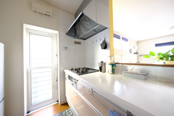 【キッチン】勝手口のあるキッチンスペース、右手にパントリー収納・リビングを見渡すカウンター